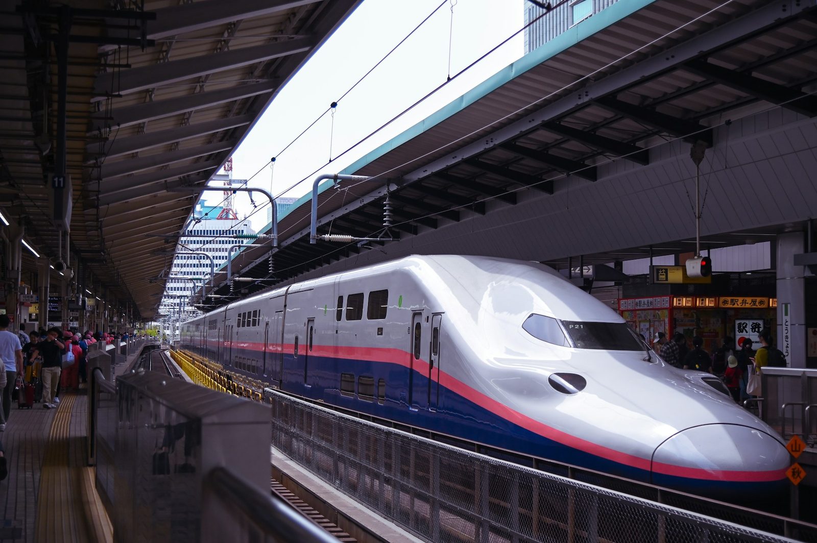 Travelers on a station platform next to a Shinkansen bullet train in Japan