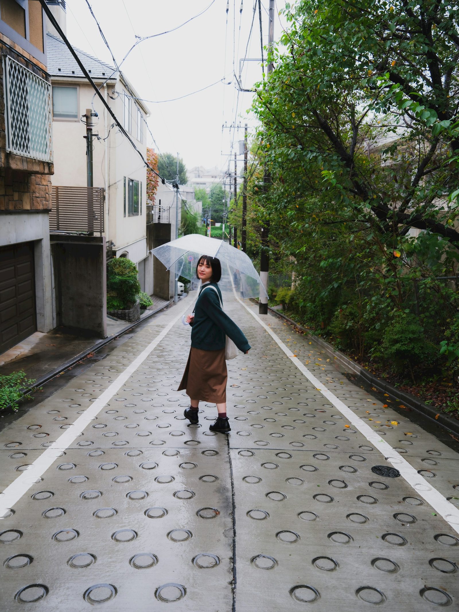 Woman with a clear umbrella walking a quiet residential street in Tokyo